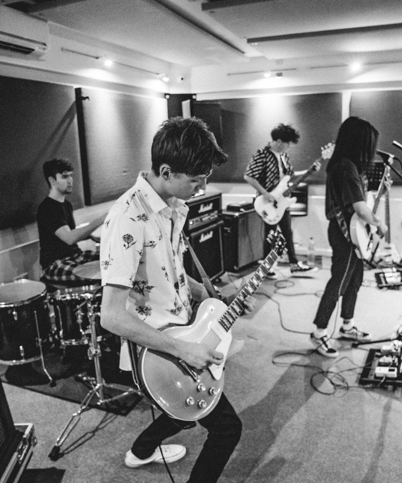 Musicians practising guitar and drums in a rehearsal room